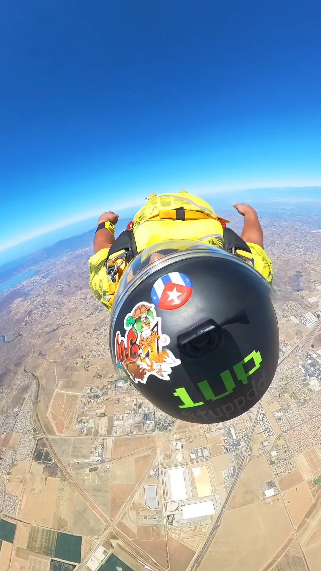 Eddy skydiving in a yellow outfit and black helmet above the landscape