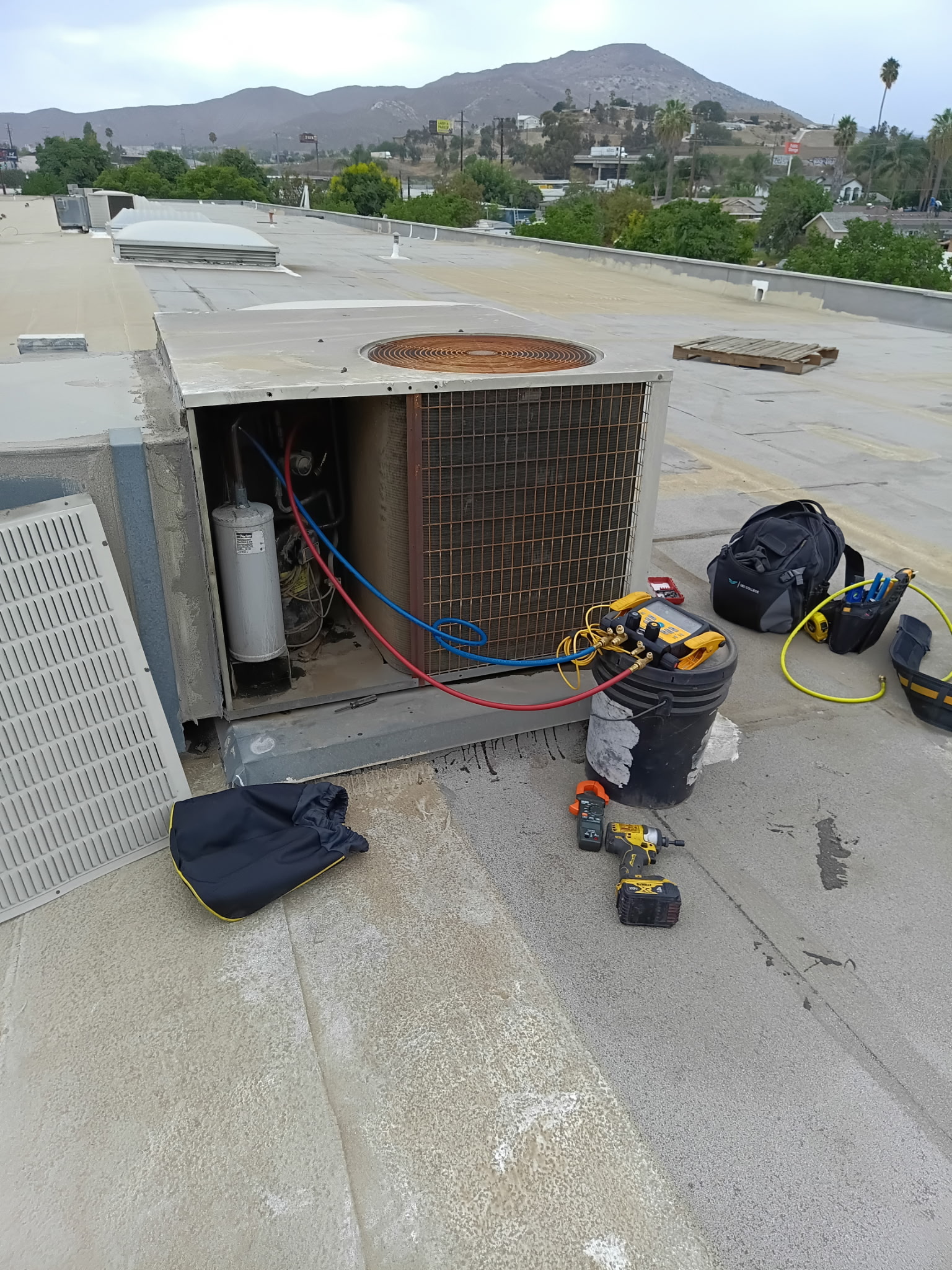 Refrigerant gauges and diagnostic tools connected to rooftop equipment.